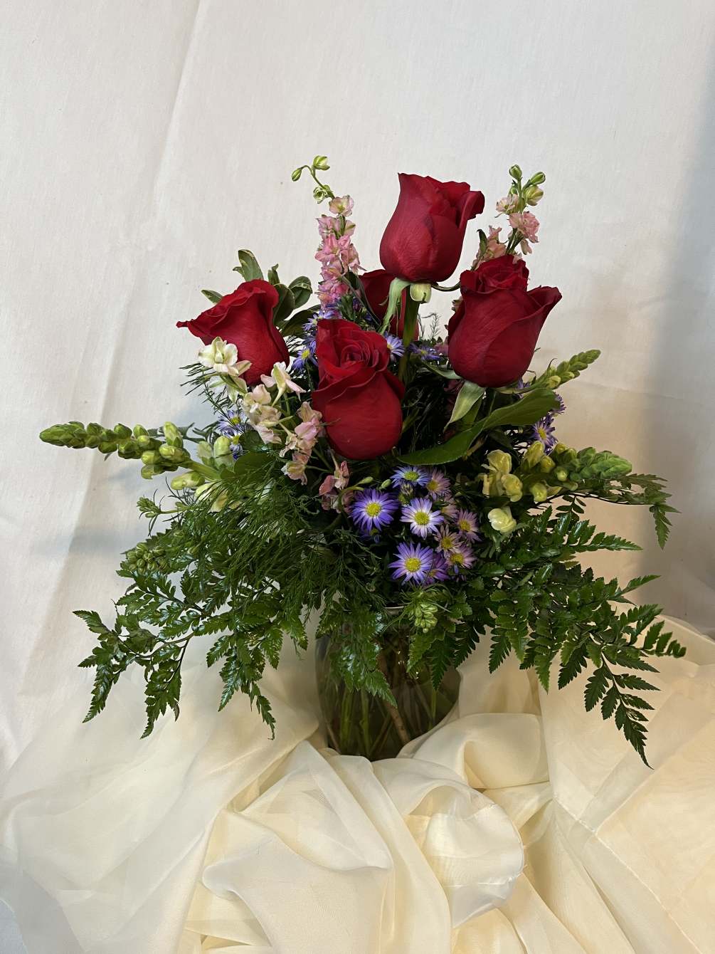 Lovely red roses, pink larkspur, white snapdragons, and purple status with luscious