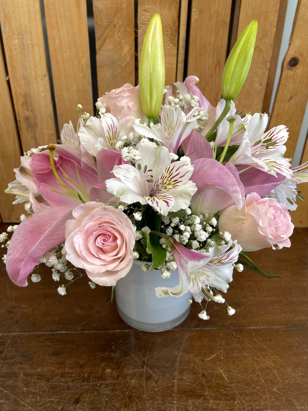 This lovely arrangement features delicate light pink and white blooms, including roses