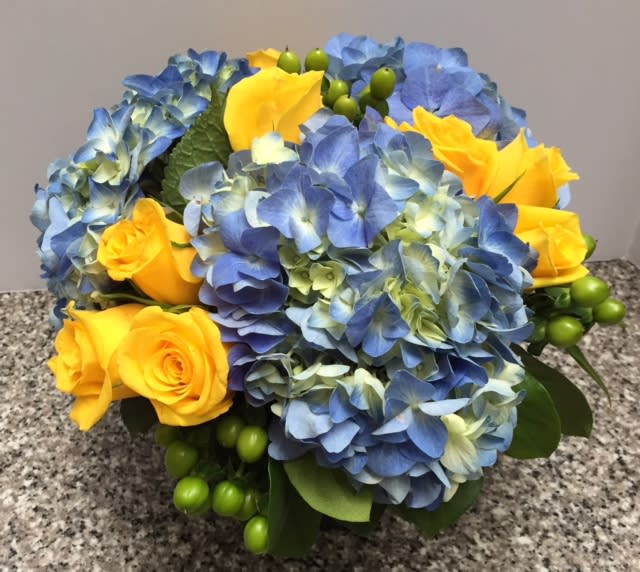 A classic combination of blue hydrangea with yellow roses. Arrangement arrives in