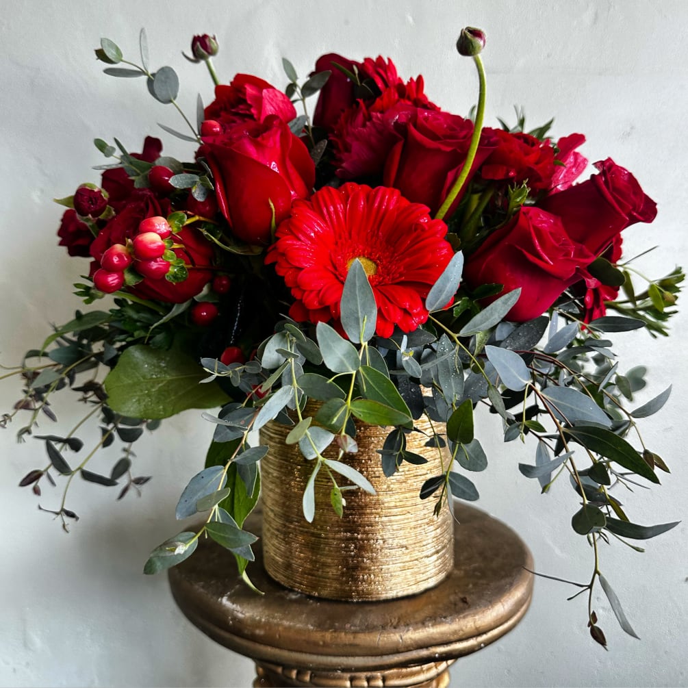 An exquisite mixture of premium red florals in a gold cylinder for