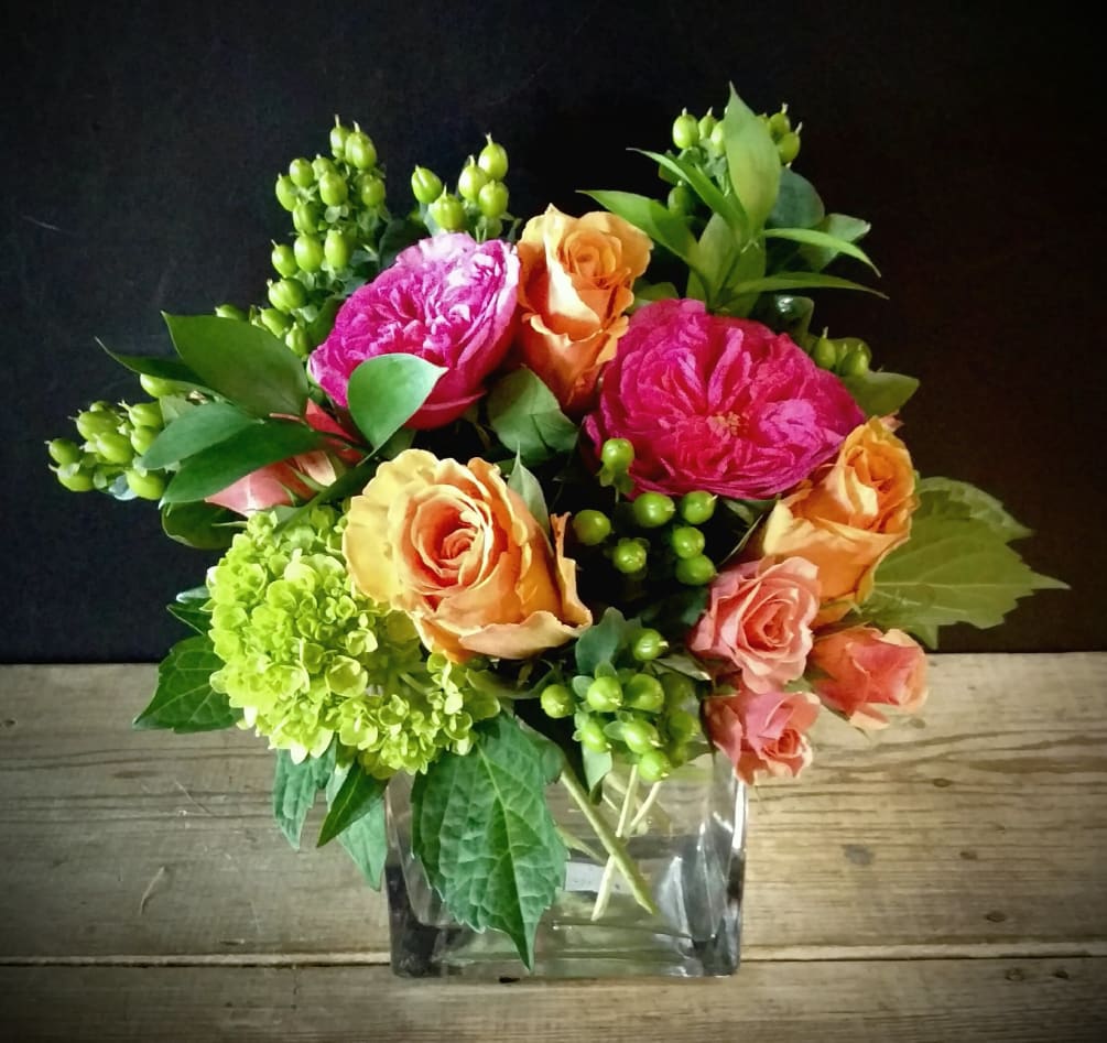 A vibrant gathering of peach roses, hot pink garden roses and immature