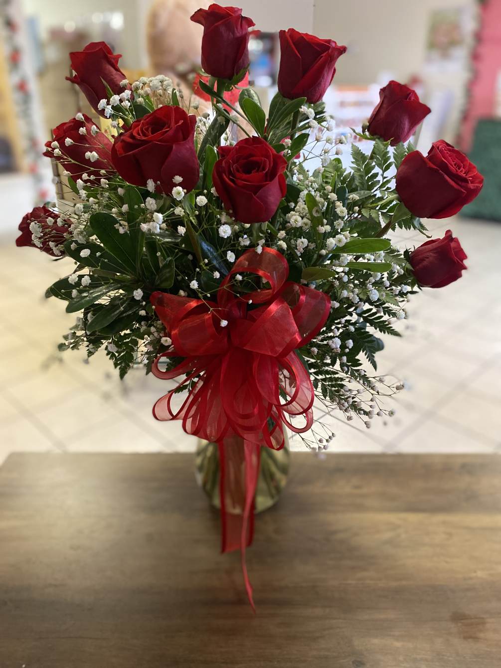 Twelve beautiful red roses arranged in a vase with baby&rsquo;s breath. Topped