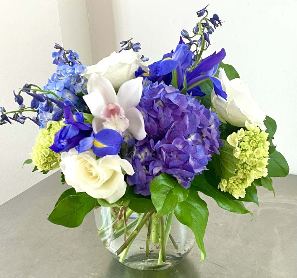 Purple, blue and green hydrangeas, roses, delphinium, iris and orchids in a
