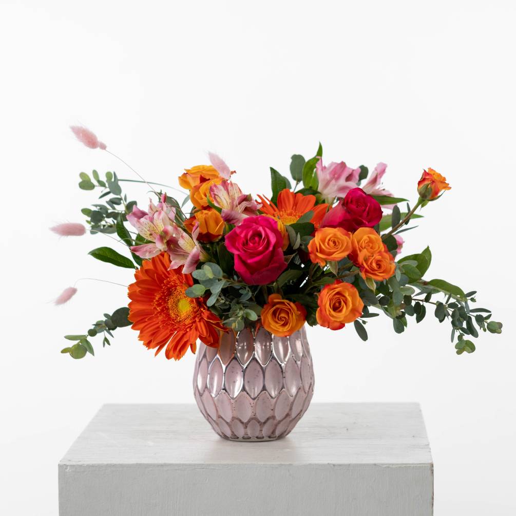 Bursting with vibrant hot pinks, pinks and zesty oranges, this floral arrangement