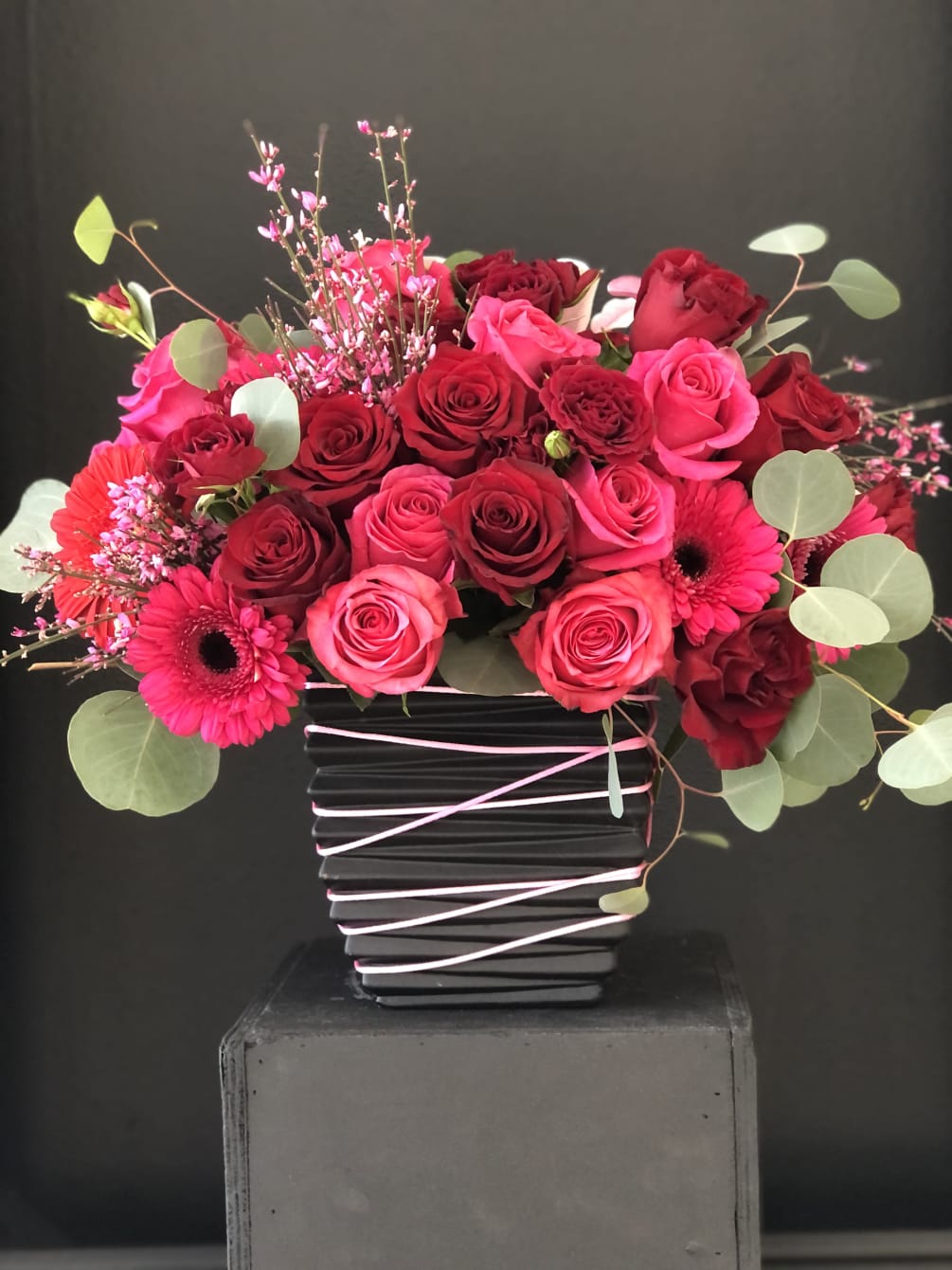 Red and pink roses, daisies beautifully arranged  in black vase, decorated