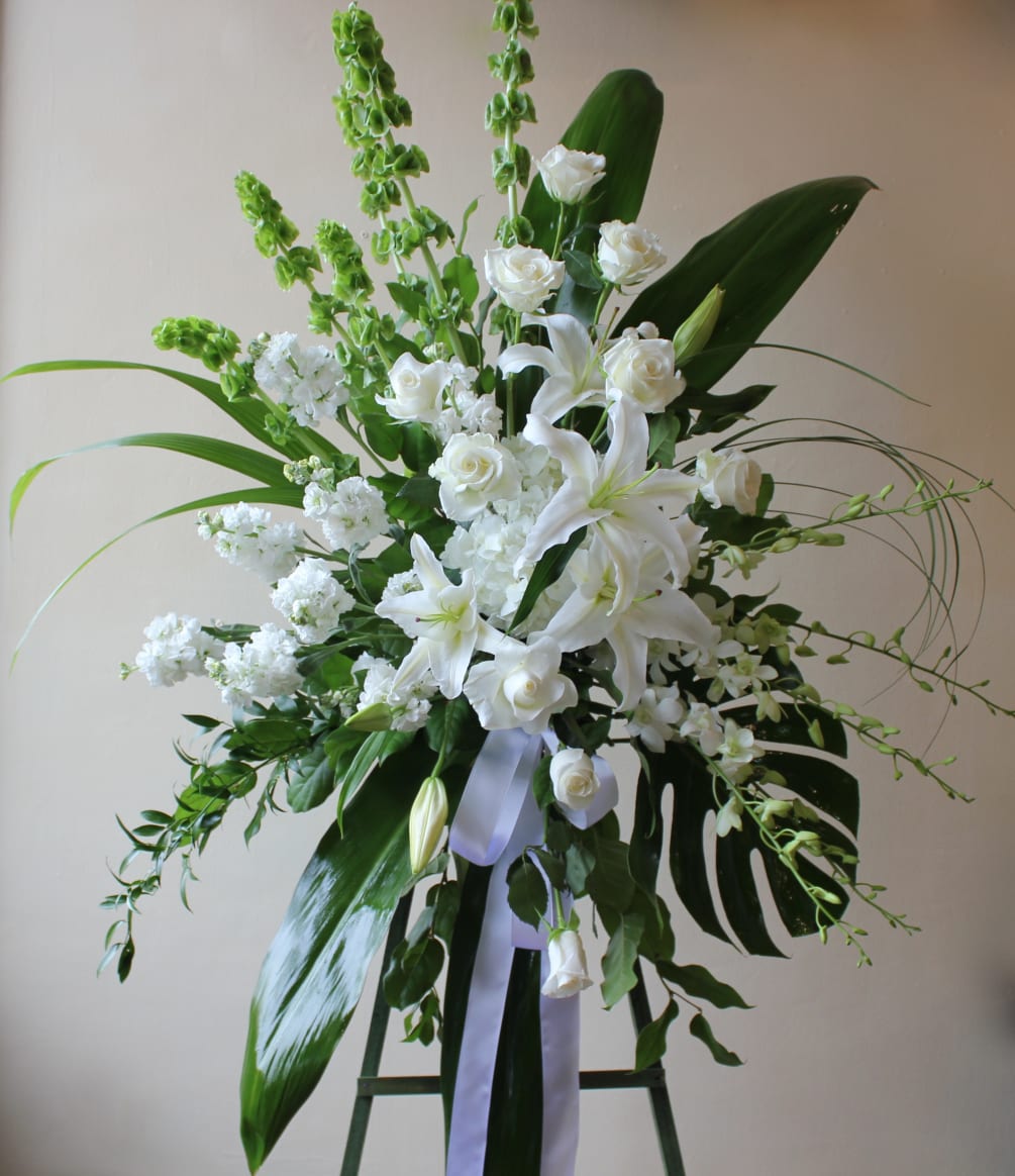 A classic standing sympathy spray including lilies, roses, stock and tropical leaves.
Can