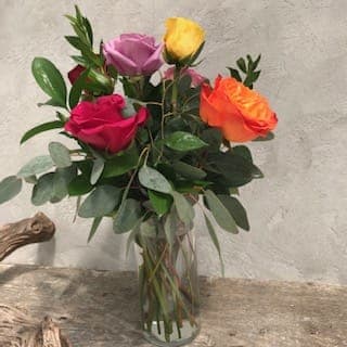 You choose the color. Six long stem roses arranged in a clear