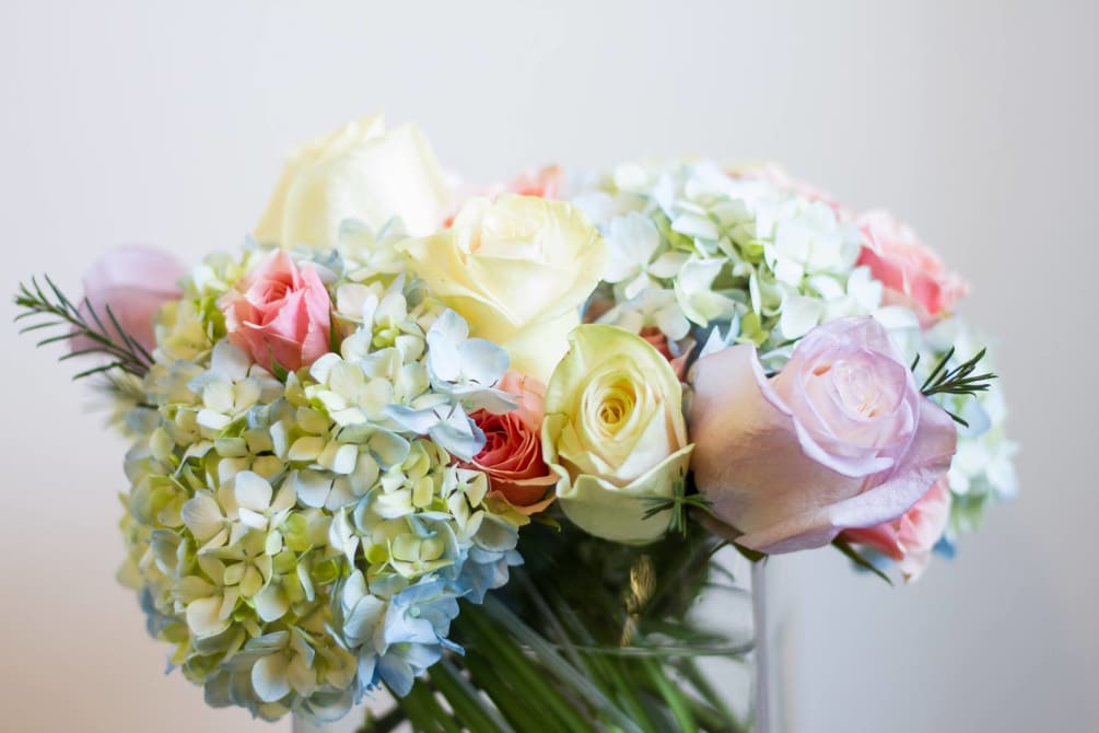An arrangement of Pastel Roses, Spray Roses and Hydrangea in a cube