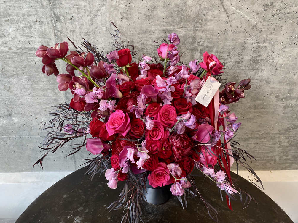 A voluminous arrangement crafted with spray roses, garden roses, peonies, sweet peas
