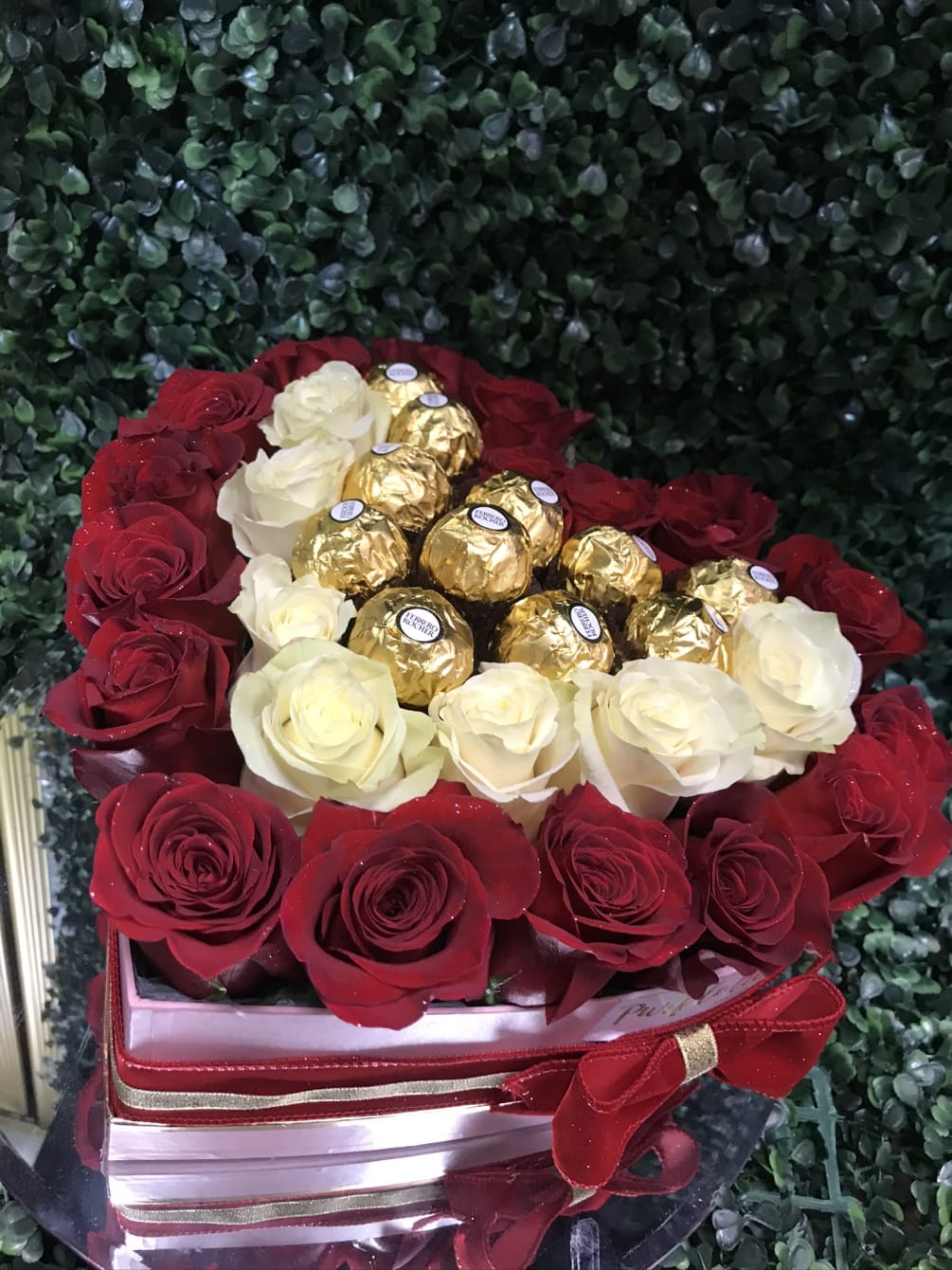 Red and white roses arranged in a heart shaped box complemented with
