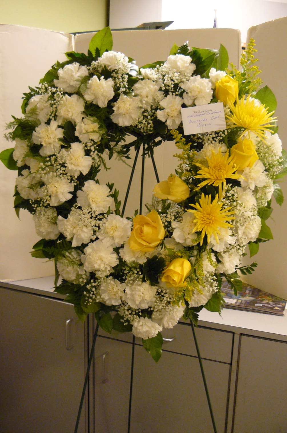 White Carnations, Yellow Roses, Fancy Assorted Greens.