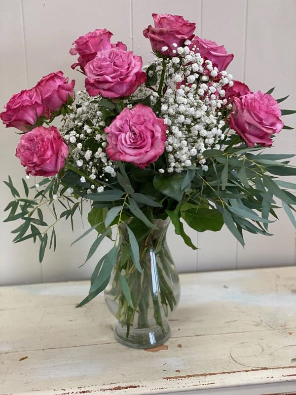 One dozen Lavender rose artfully arranged in a vase with accent flower