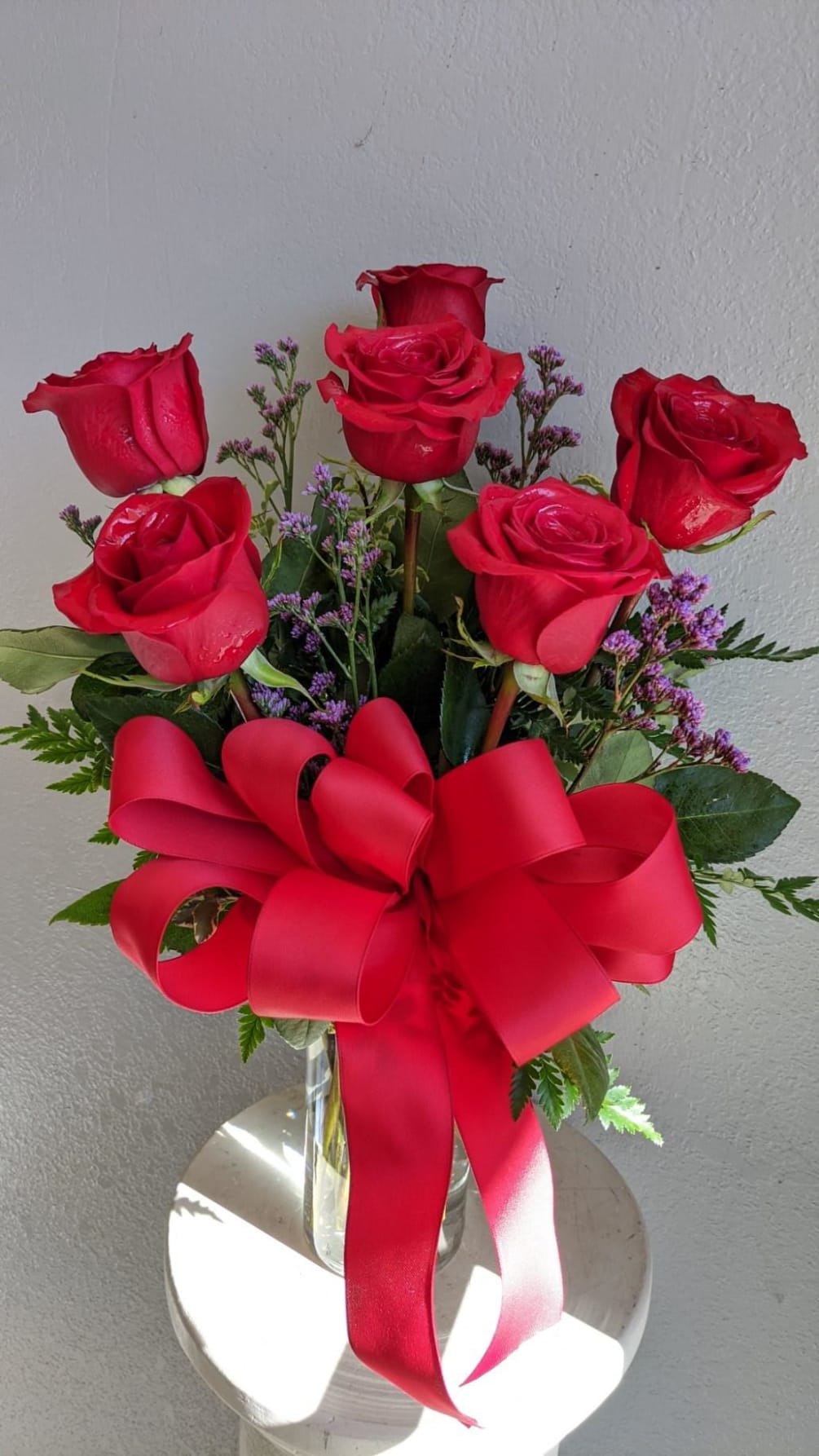6 long stem red roses arranged in a vase with filler and