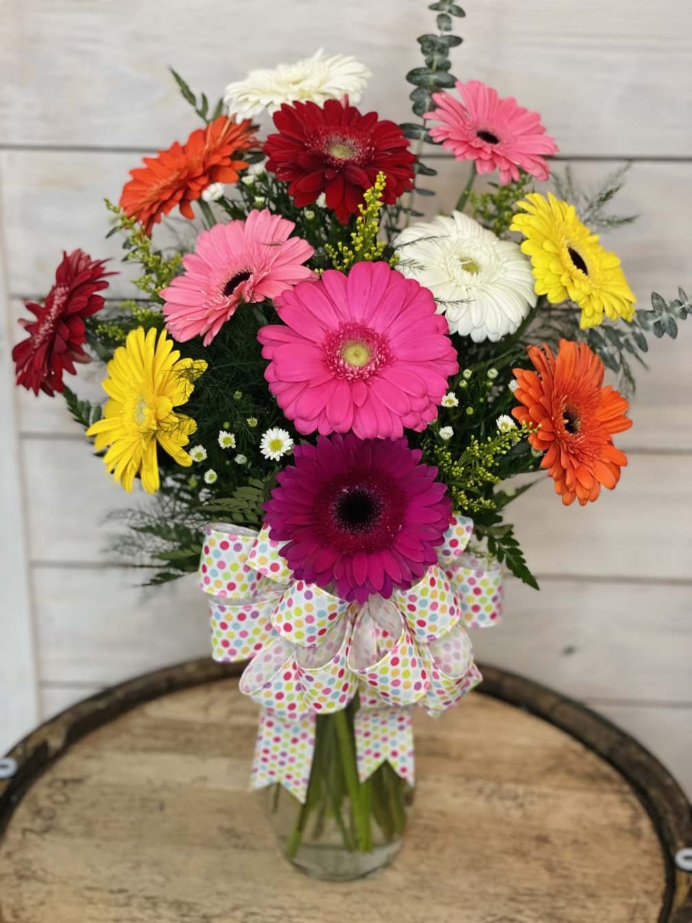 A stunning and colorful variety of 12 gerbs with filler flower arranged