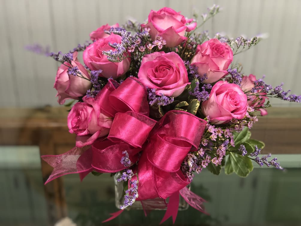 A dozen pink roses with pink and purple field flowers arranged in