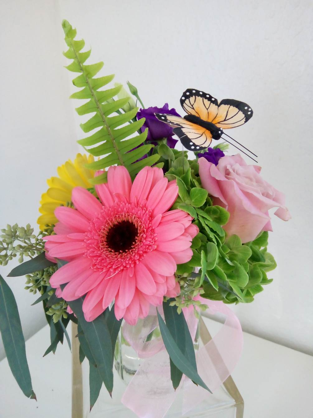 Bright color roses and gerberas in a mason jar with a butterfly