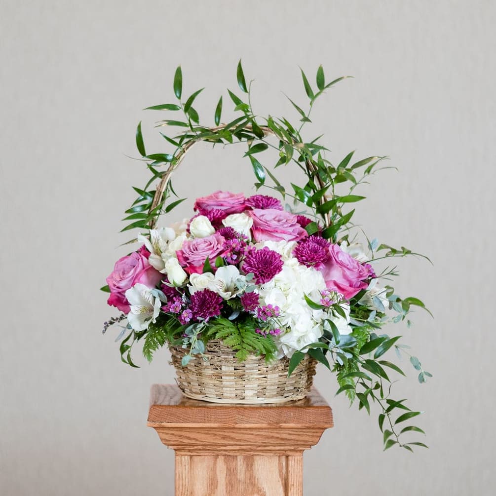 A traditional basket arrangement overflowing with feminine roses, fluffy hydrangea and long