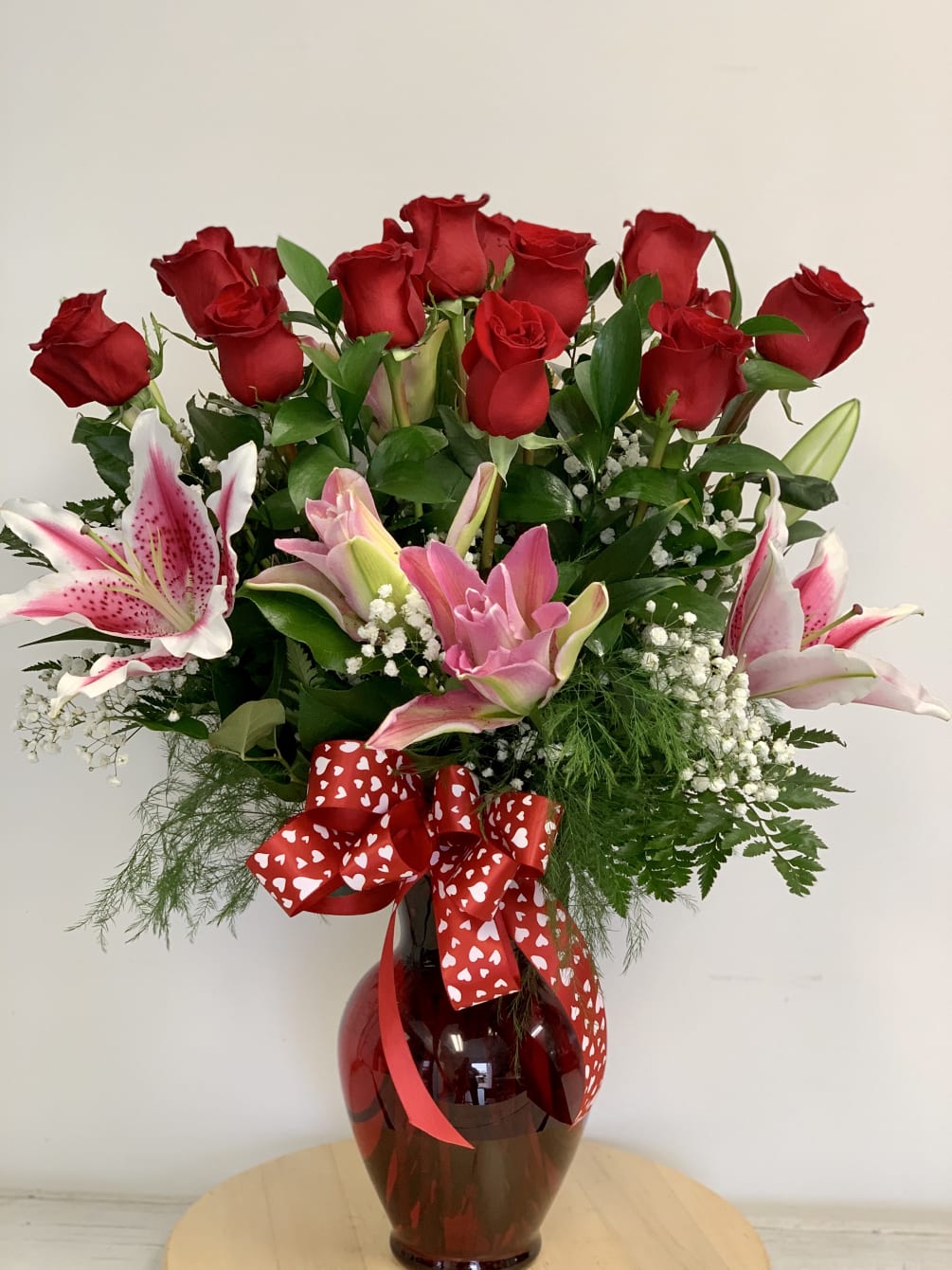 Pink lilies arranged with dozen red roses