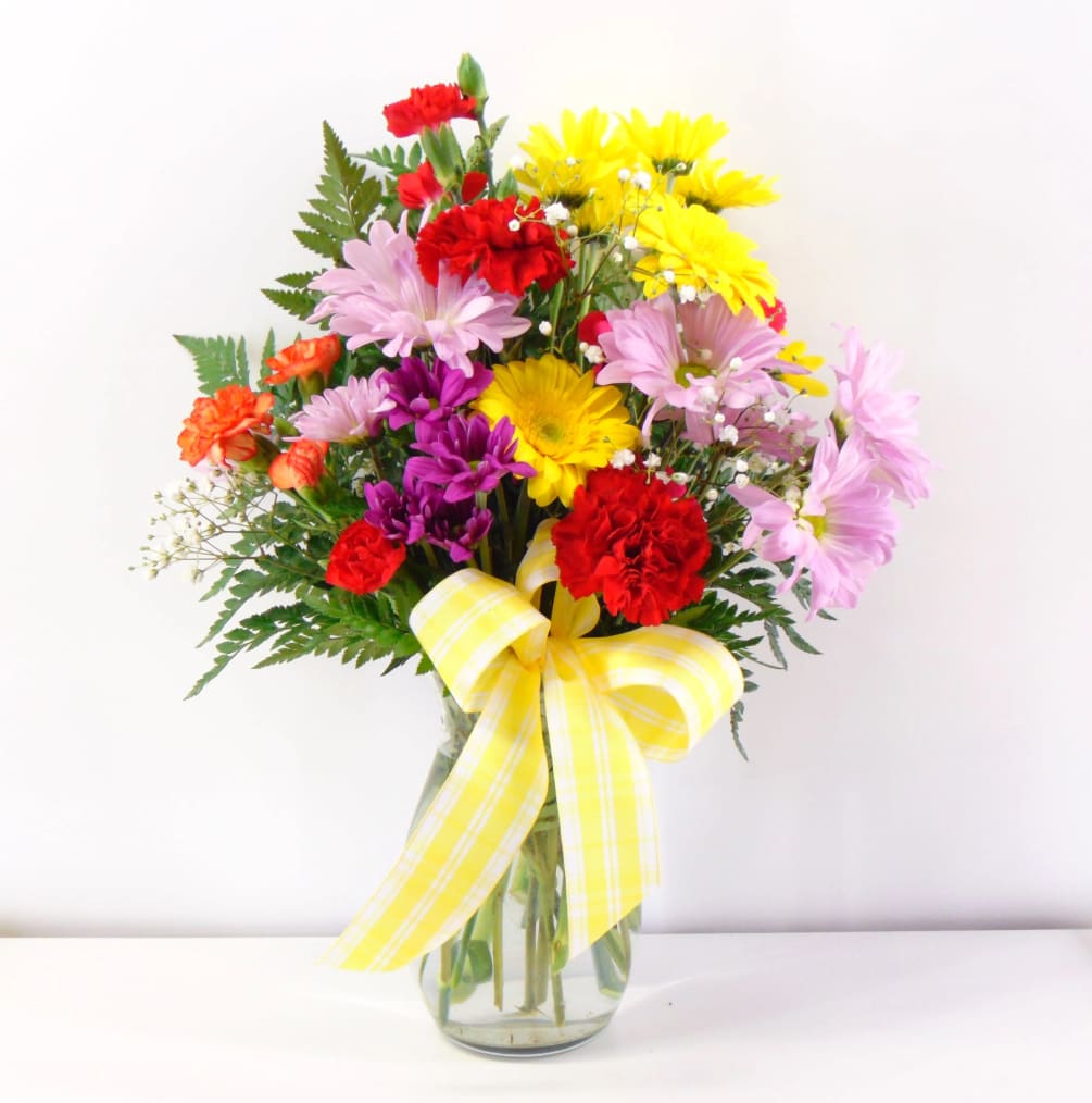 Colorful blooms of daisies, gerberas, stock and carnations with a sunny bow