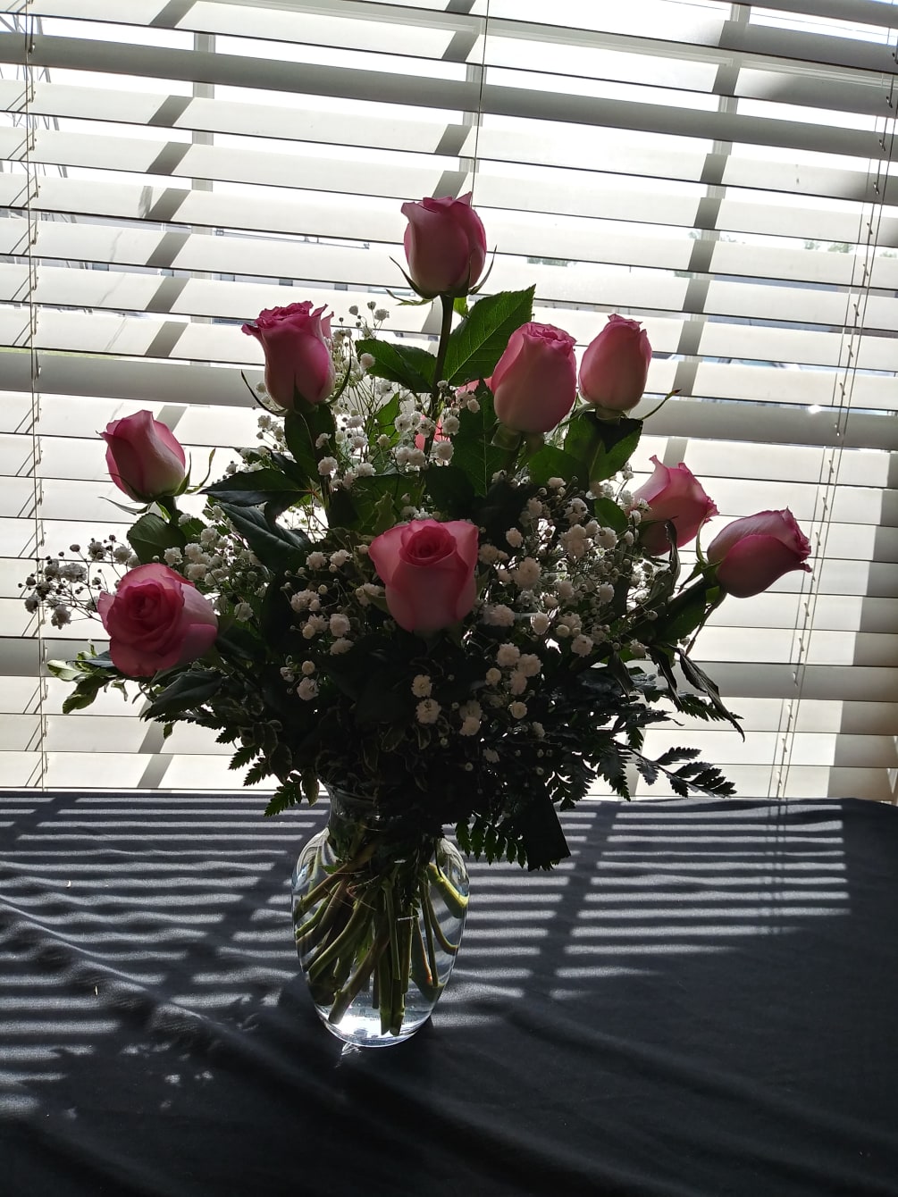 Pink rose in clear vase with greenery and highlighted with filler Flowers