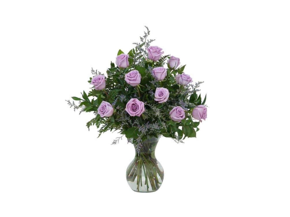 Lavender Roses and soft accent flowers designed in a clear glass vase.
