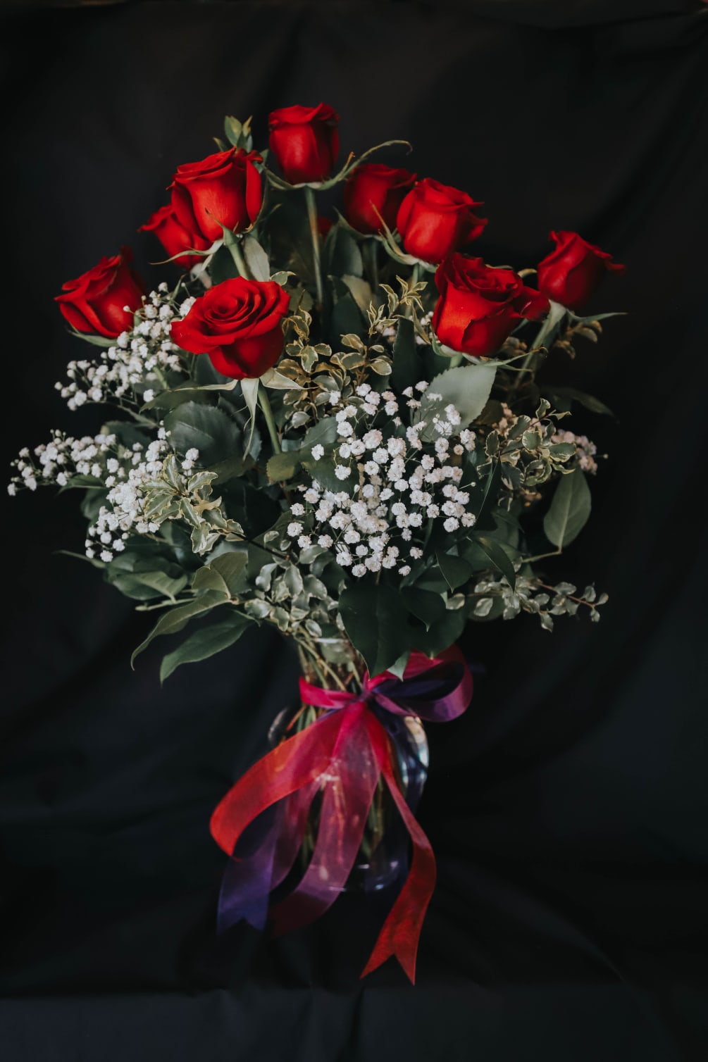 12 beautiful, velvety red roses designed in a vase with premium greenery