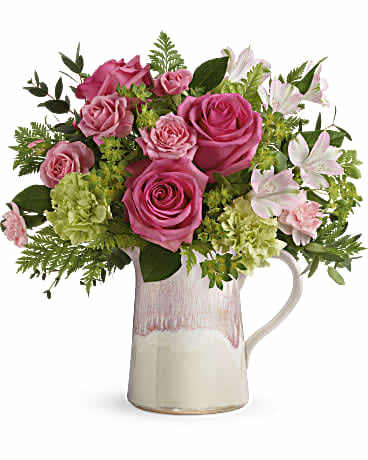 Beautiful spring blooms are arranged in a stylish stoneware pitcher that features