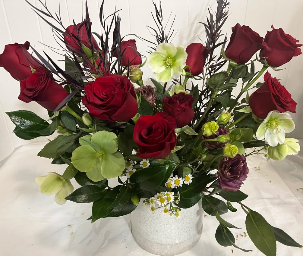 A dozen (12 stems) of red roses, adorned with seasonal greenery, foliage
