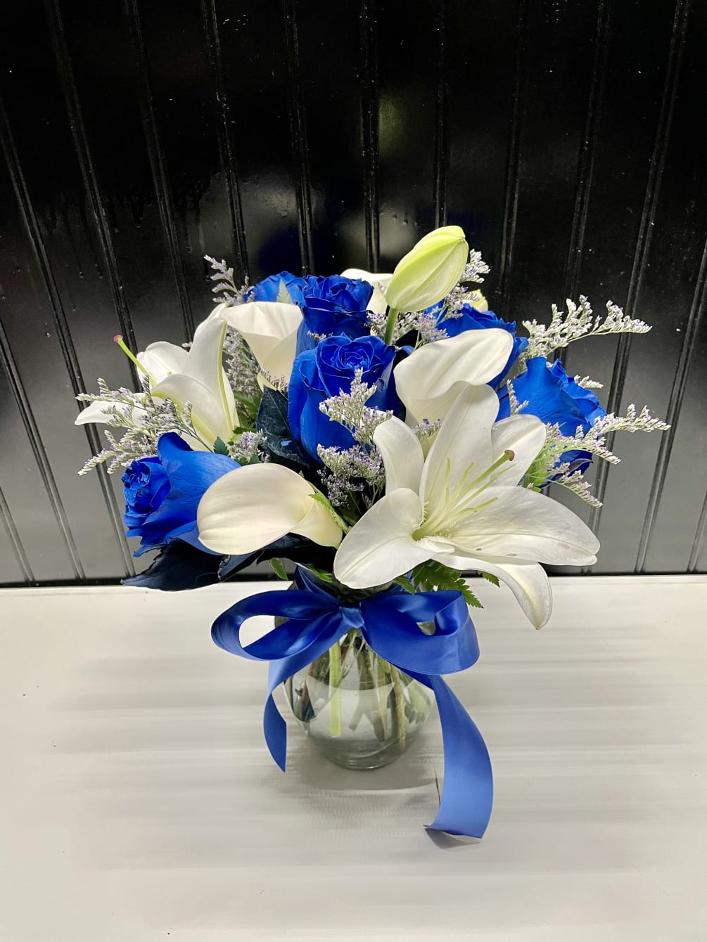 A beautiful arrangement short and compact with blue roses and white calla