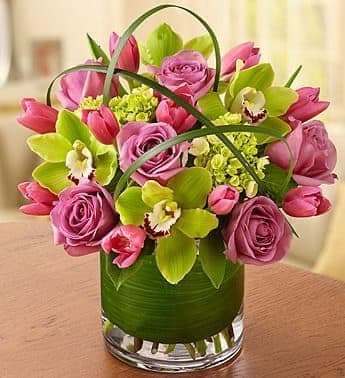 Cool water roses, green cymbidium orchids in a leaf lines glass cylinder