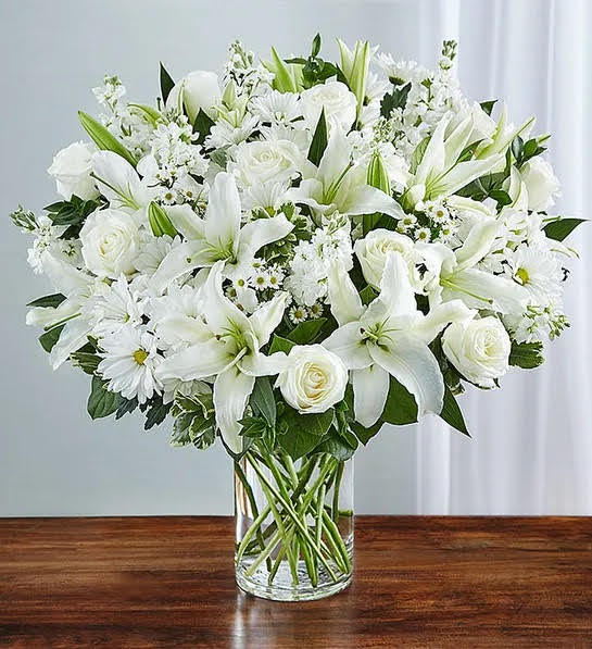The bouquet includes fresh white roses, lilies, stock, daisy poms and monte