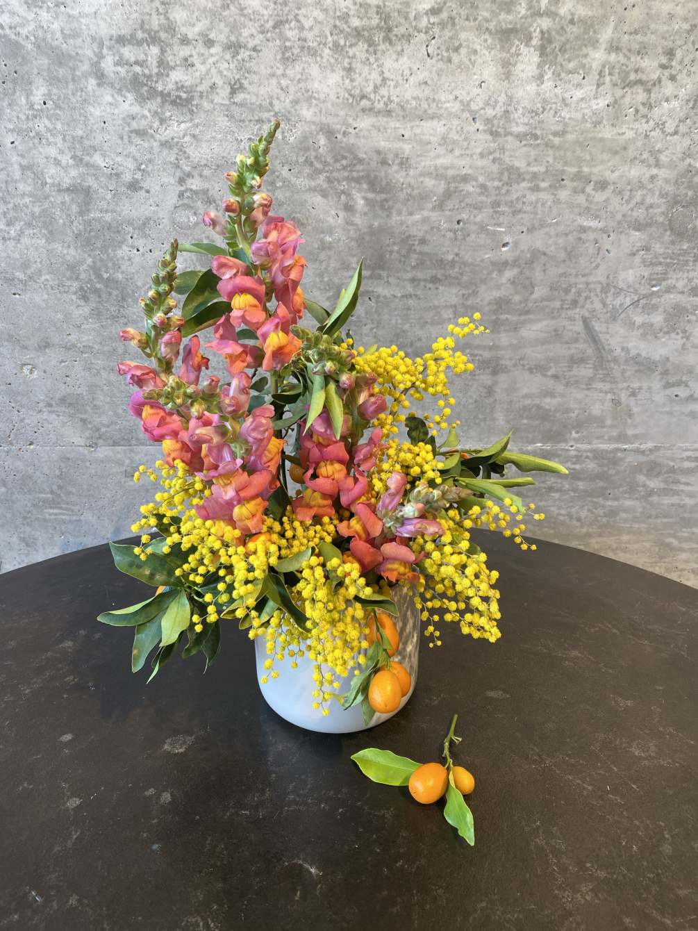 A petit mix of snap dragons, citrus, and bright yellow accents (blooming