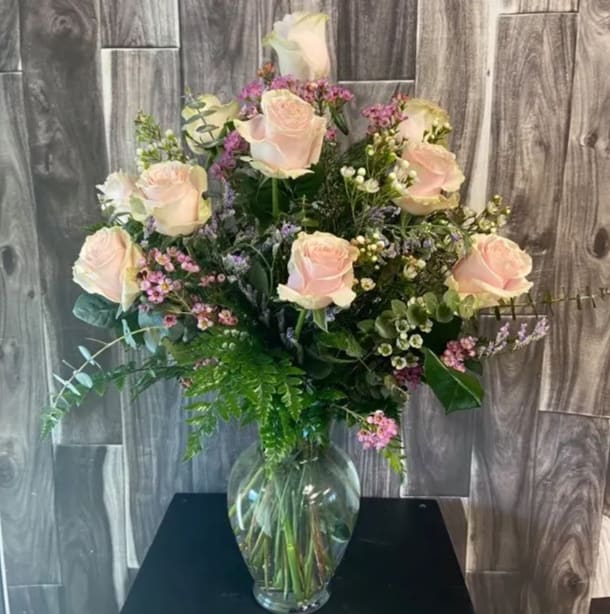 One dozen colored roses in a vase with filler and greenery, when