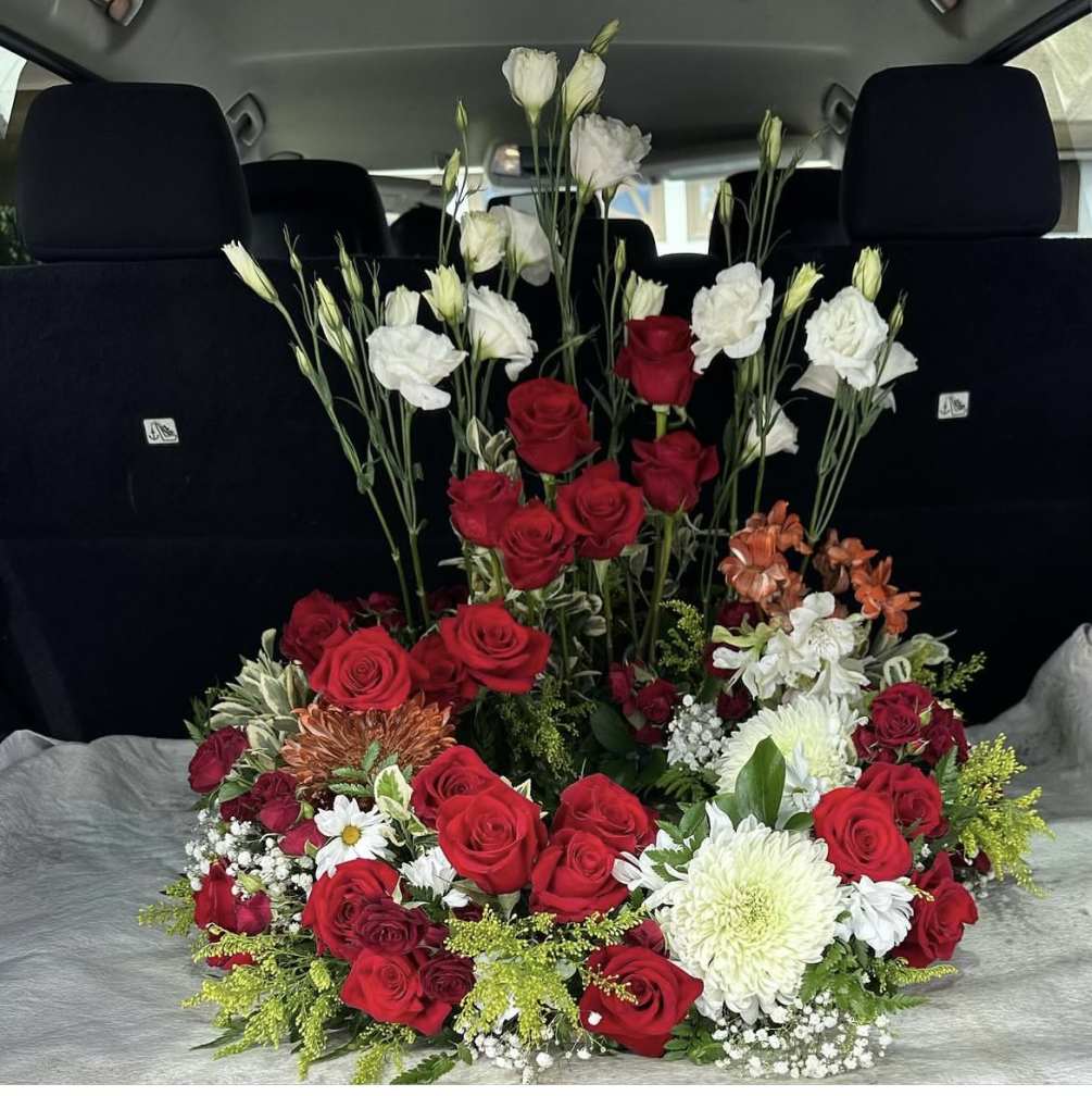 This beautifully arranged memorial design consist of roses, lilies, ranunculus, mums, and