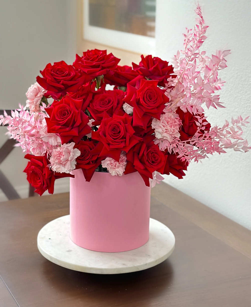 Large red roses, soft pink dianthus, and elegant ruskus will not leave