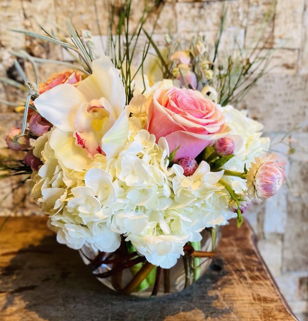 This soft and feminine arrangement consists of hydrangeas, roses and cymbidium orchids.