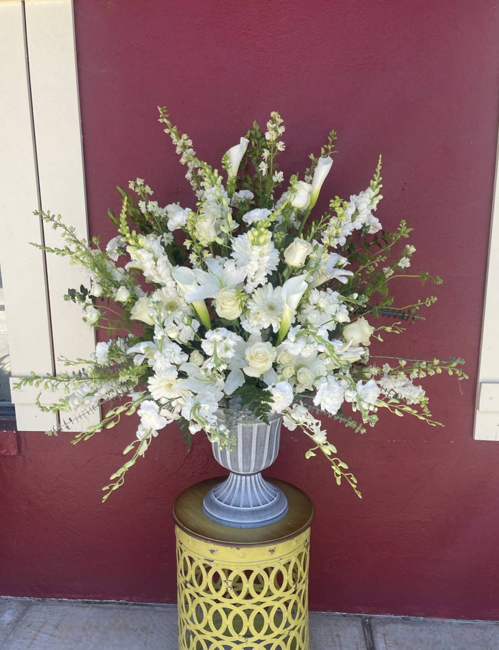Beautiful seasonal flowers congregate in a large urn. This arrangement is appropriate