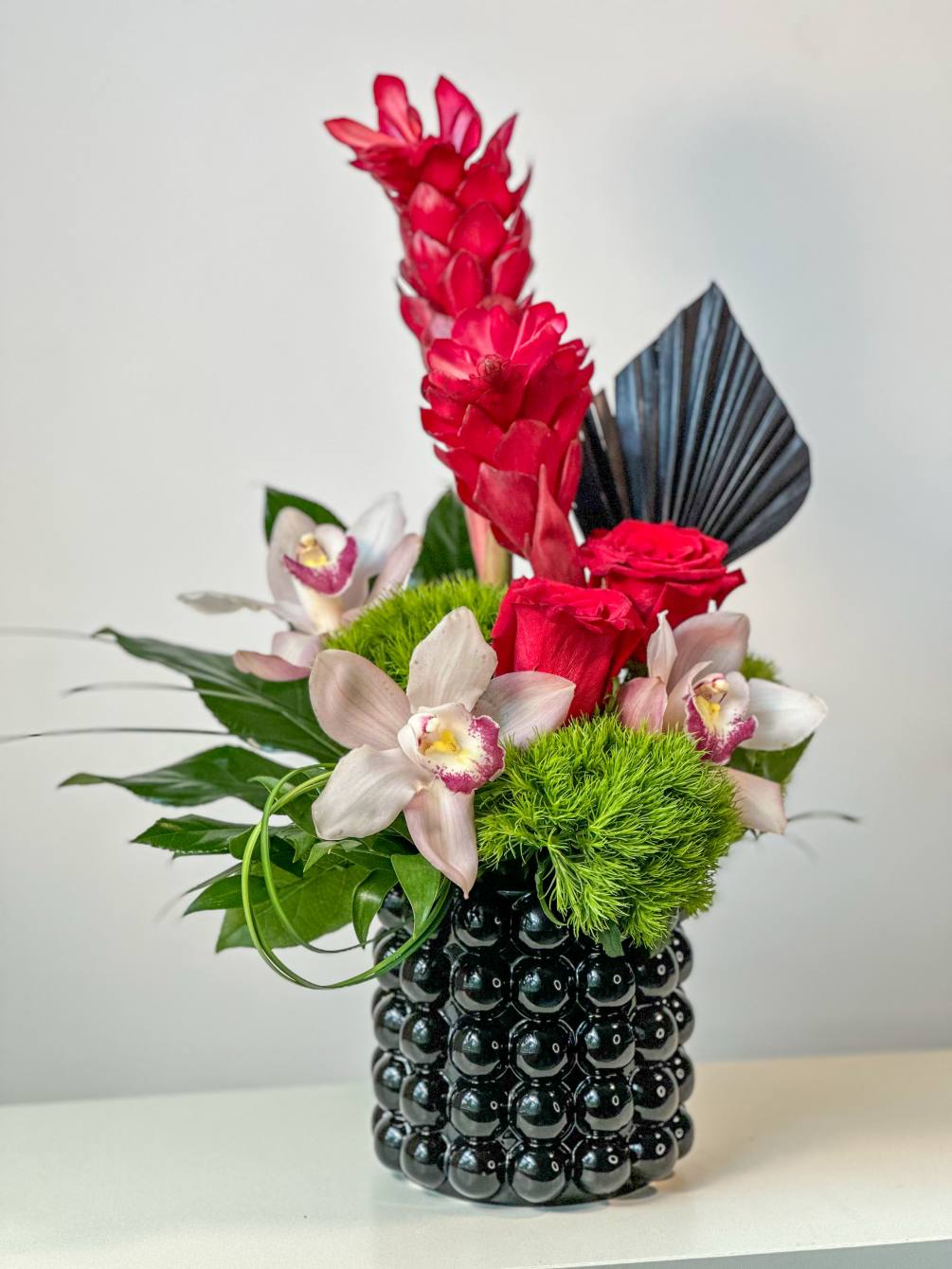 The vibrant combination of Ginger, Red Roses, and Cymbidium Orchid, paired with
