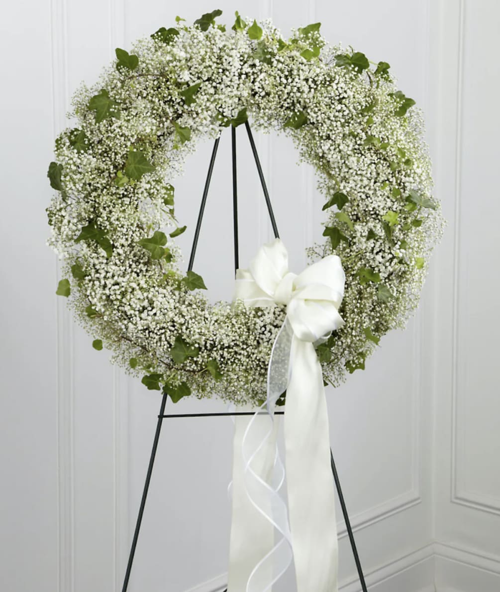 A lush open wreath of babies breath and greens with a trailing