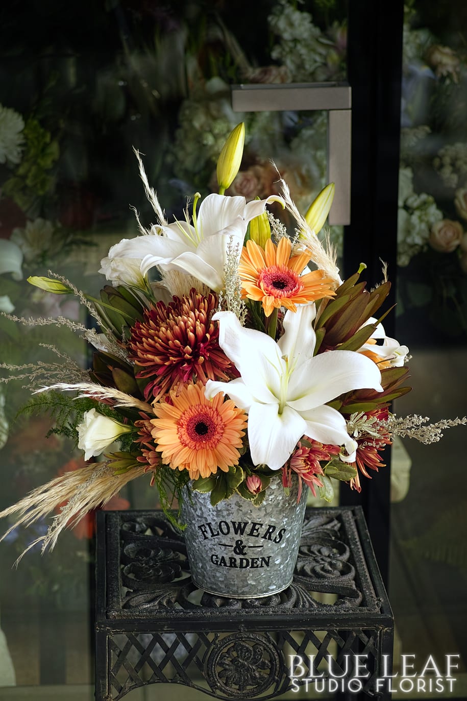 A festive fall arrangement designed in a galvanized tin. Bright white lilies