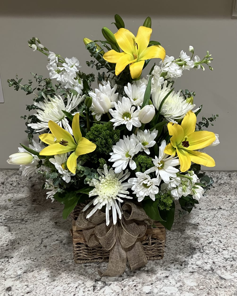 A cute basket of yellow Lilies and white Daisies.
