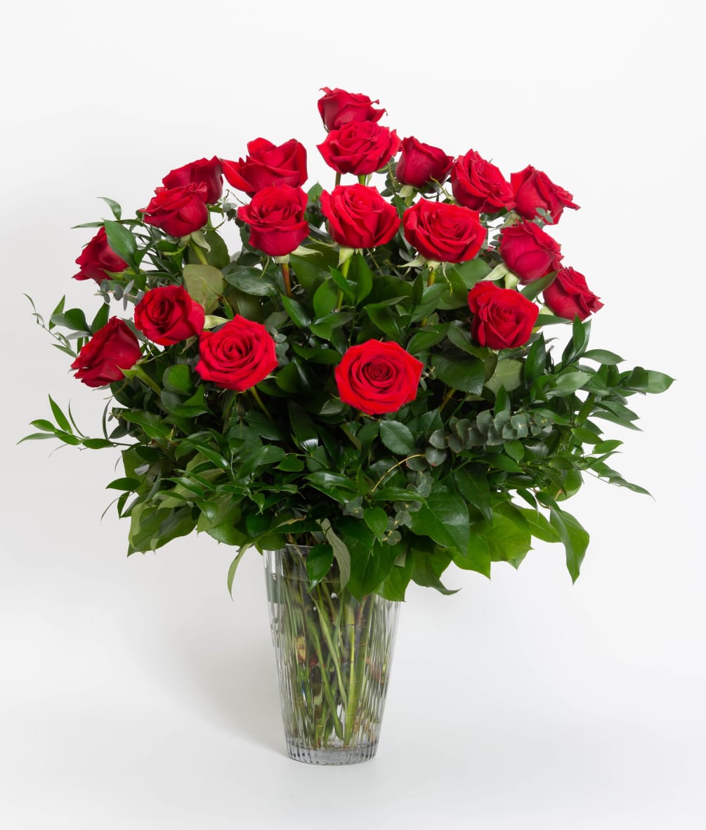 Two dozen long stem red roses arranged in a vase with decorative