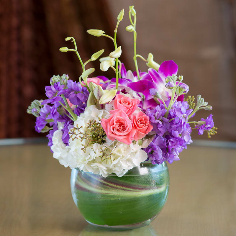 A bouquet with coral roses, purple dendrobium orchids, hydrangeas and fragrant lavender