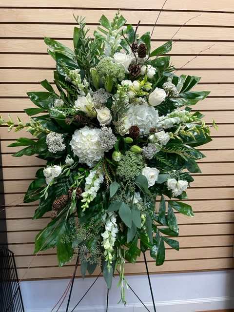 Mixed greenery with white and cream flowers accented with pine cones and