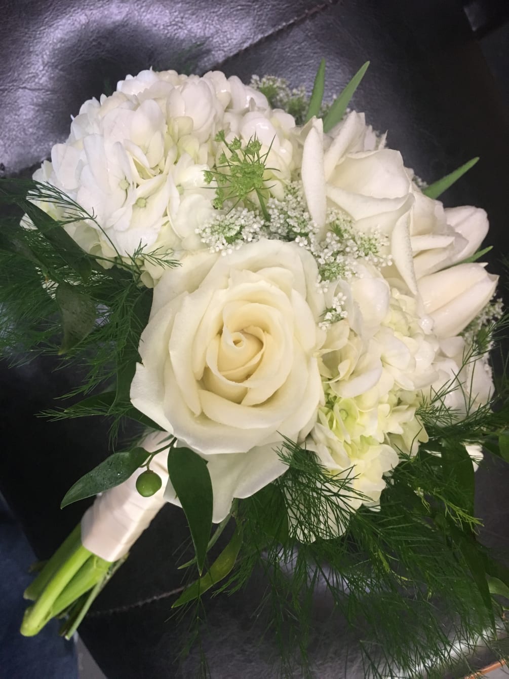 Creamy white flowers gathered in a nosegay. Flowers are accented with seasonal