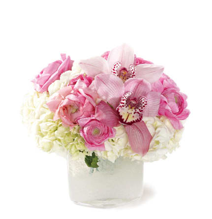 White cube or cylinder filled with ranunculus, cymbidium and hydrangea in these