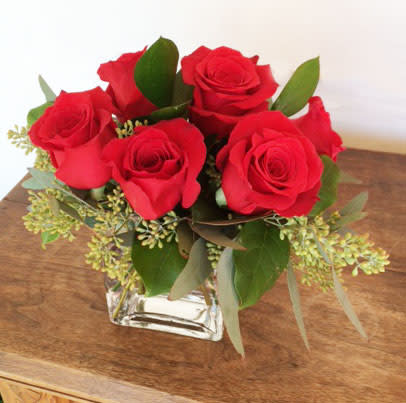 1/2 doz red roses accented with assorted greenery in a simply glass