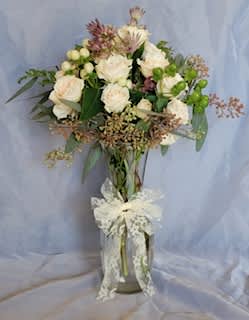 A sweet arrangement is in a glass vase containing blush spray roses