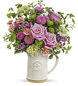 A bouquet of pinks purples and greens arranged in a blush colored