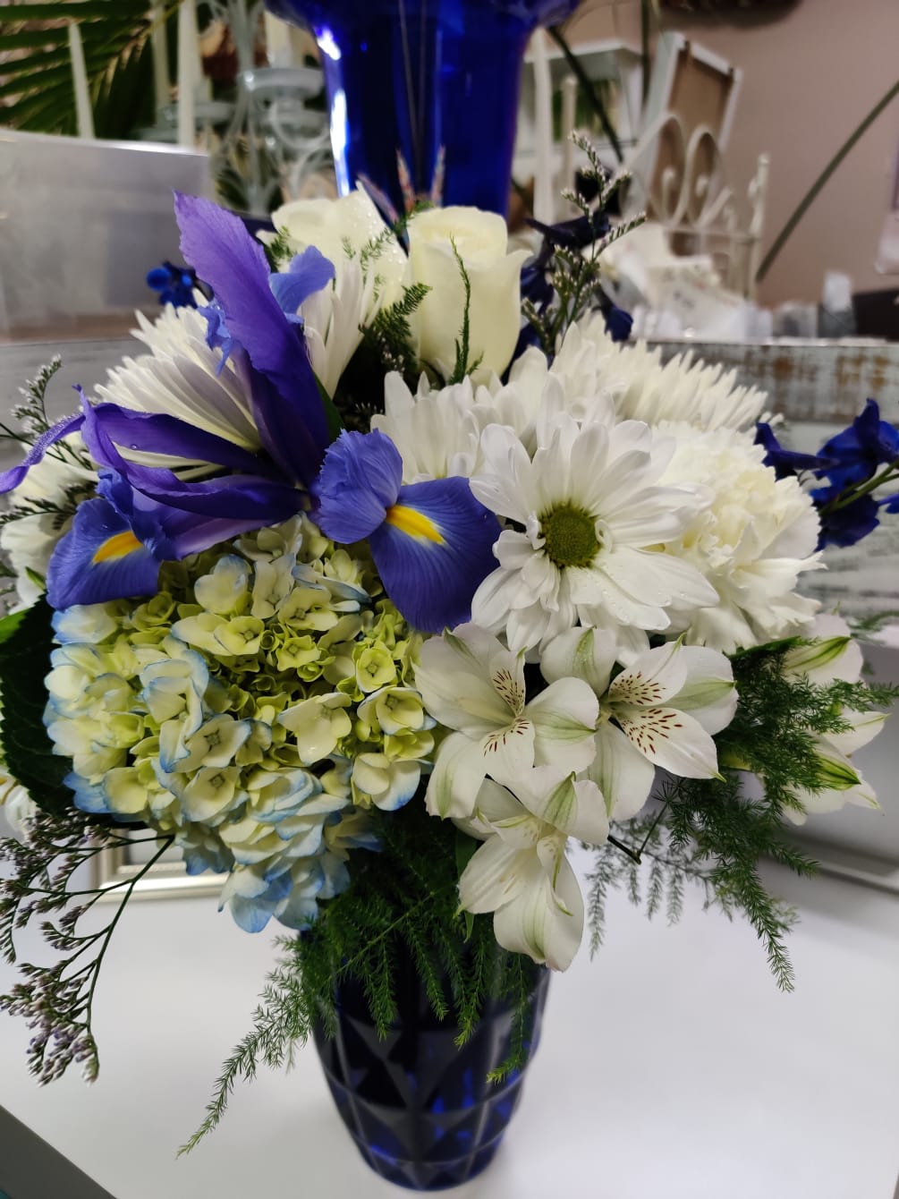 Lovely vase arrangement, designed beautifully with white roses, hydrangeas, iris, daisy poms